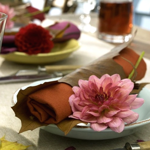 rust napkins covered with fall leaves and with pink blooms will make your tablescape cool and chic, very fall-like