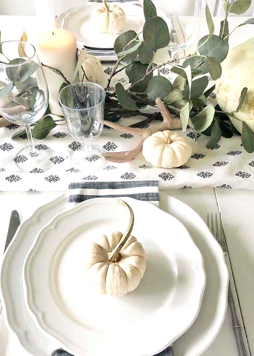 a lovely neutral Thanksgiving place setting with vintage plates, a striped napkin, silver and a small pumpkin on top is cool