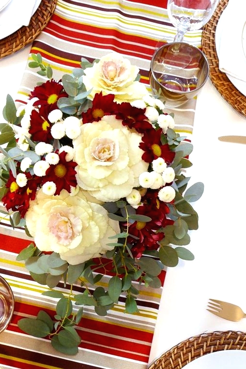 a bright Thanksgiving centerpiece of neutral and burgundy blooms, greenery and candles around is amazing