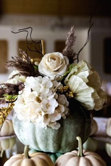 a delicate pastel Thanksgiving centerpiece of a green pumpkin, neutral blooms, berries, dried grasses is amazing