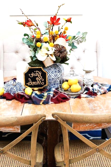 a super bold Thanksgiving centerpiece of white, red blooms, greenery, billy balls, a vine pumpkin and pillar candles