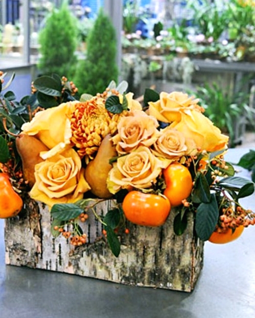 a bright fall or Thanksgiving centerpiece of a birch box, orange blooms and matching orange fruit and greenery is a cool idea for the fall
