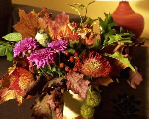 a decadent fall or Thanksgiving centerpiece of pink, burgundy blooms, berries, dark fall leaves is a catchy and chic idea