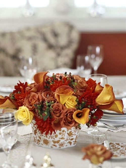 a bold Thanksgiving centerpiece of burgundy, red and yellow blooms and greenery is a cool touch of color to the space