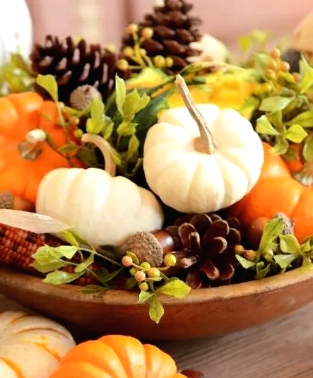 a bright rustic Thanksgiving centerpiece of a wooden bowl, pinecones, acorns, corn cobs, greenery and gourds is a very cool idea