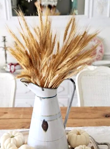 a perfect rustic and shabby chic Thanksgiving arrangement of wheat in an old jug, white gourds around is amazing