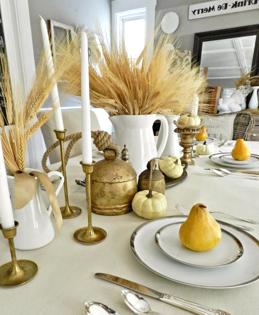 a rustic vintage cluster Thanksgiving centerpiece of wheat, candles, pumpkins and vintage brass touches is chic