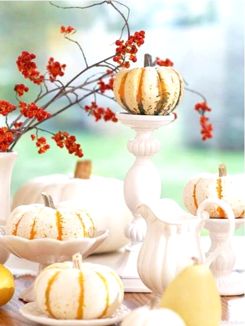 a Thanksgiving centerpiece of some small pumpkins on plates and stands and bold berries on branches is a classy rustic and vintage idea
