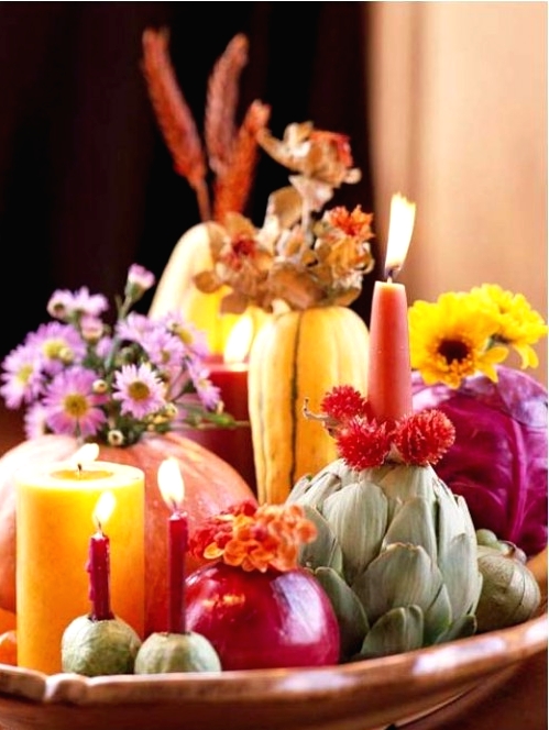 a bright and catchy Thanksgiving centerpiece of a bowl with fresh real veggies, bold blooms, dried and fresh ones, and colorful candles