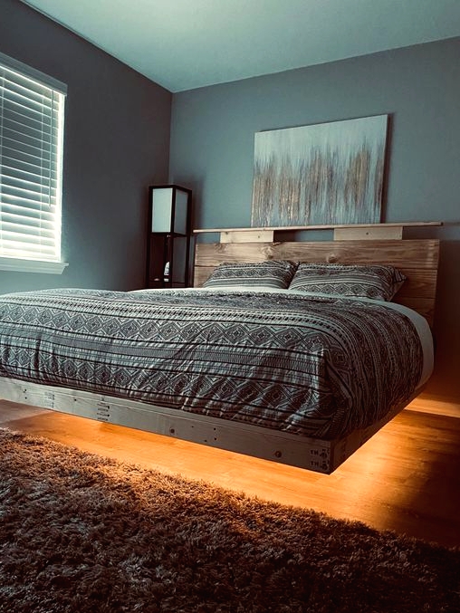a lit up floating bed with printed bedding and a wooden headboard is a stylish idea for a modern bedroom and this light will create an ambience