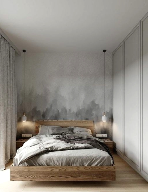 a neutral bedroom with a grey ombre accent wall, a floating light-stained bed and nightstands, pendant lamps and grey bedding