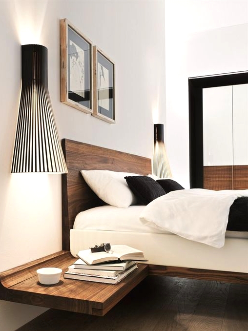 a super stylish modern bedroom with a rich-stained floating bed and matching nightstands, catchy black sconces and a duo of artworks