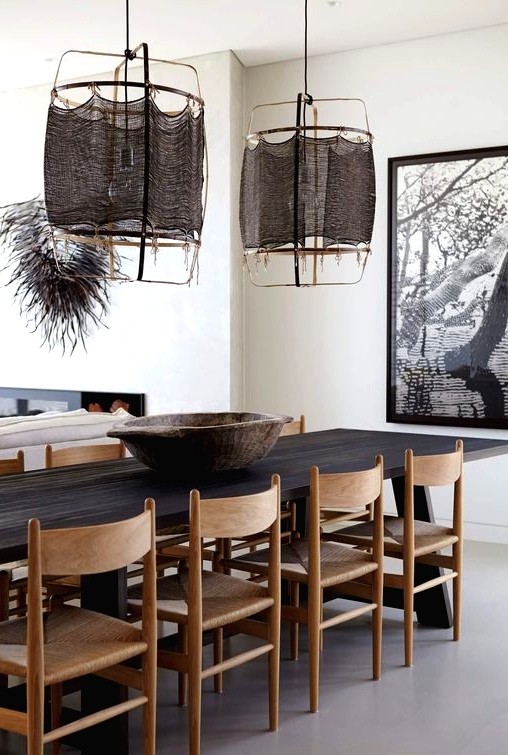a bold and catchy dining space with a dark-stained dining table, light-stained chairs, dark pendant lamps and a bold artwork