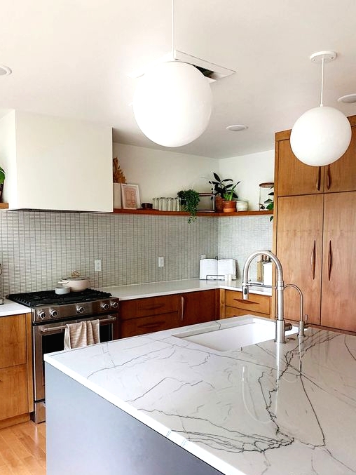 a mid-century modern kitchen with rich-stained cabinets and a white hood, a blue kitchen island and a light-stained floor