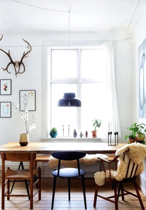 a Scandi dining space with a light-stained floor, a rich-stained table and chairs, black chairs and some potted plants is amazing