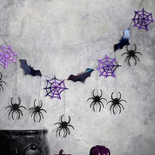 Halloween decor with a bat, purple spiderweb, spider bunting, purple pumpkins and a black cauldron with smoke is a cool idea