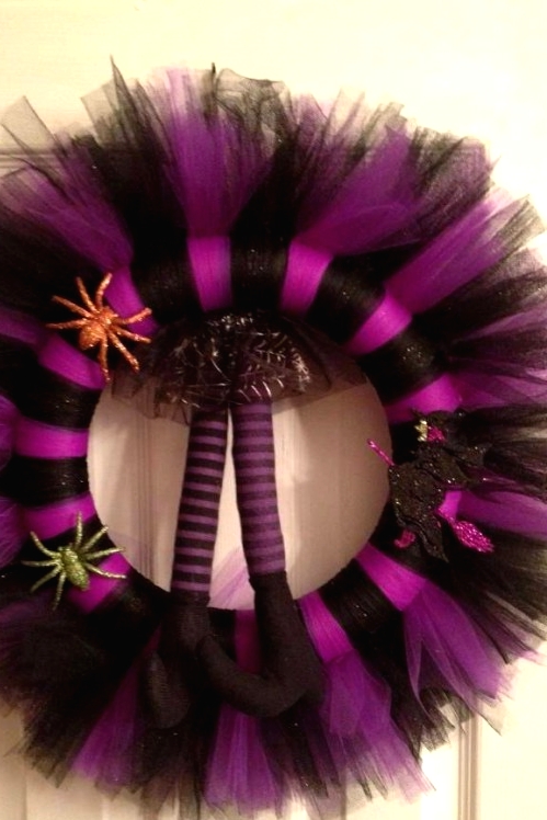 a black and purple striped Halloween wreath with glitter spiders and witches' legs is a very cool and bold idea for Halloween