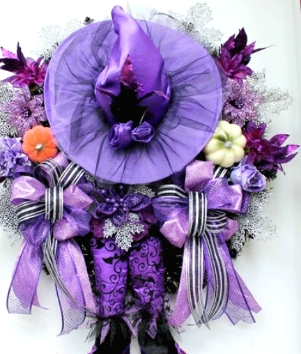a creative lilac and purple Halloween decoration with a lilac witch hat, witch's legs, pumpkins, blooms, ribbons and faux foliage is wow