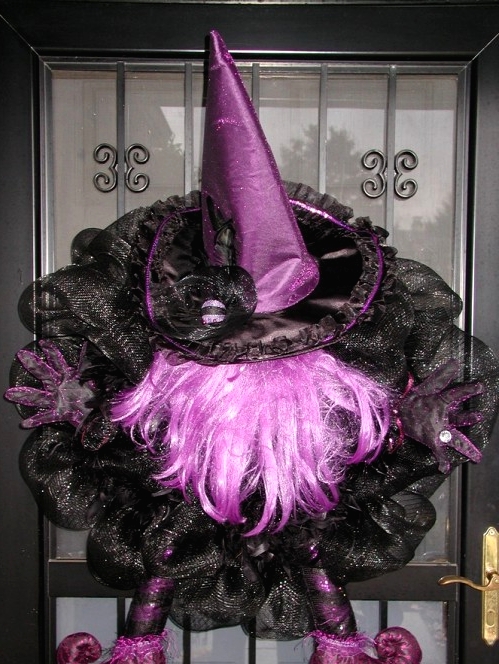 a bold black and purple Halloween decoration of black mesh ribbons, a purple witch hat, legs and some hair is a unique alternative to a usual Halloween wreath