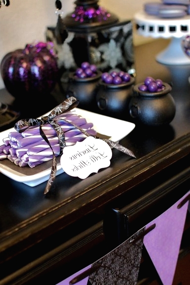a black and purple Halloween sweets table with various candies, sweets, desserts and pumpkins is a stylish and cool idea