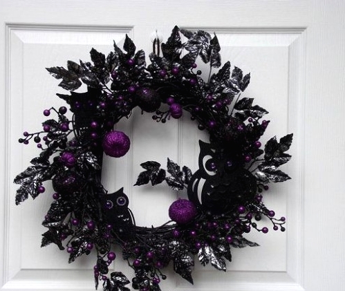 a super elegant and moody black and purple Halloween wreath with berries, apples, silhouette owls and mcuh other stuff looks refined