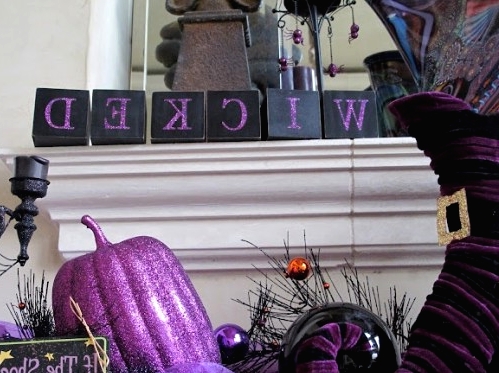 purple and black Halloween table decor with witches' legs, pumpkins, candles, spiders and WICKED letters