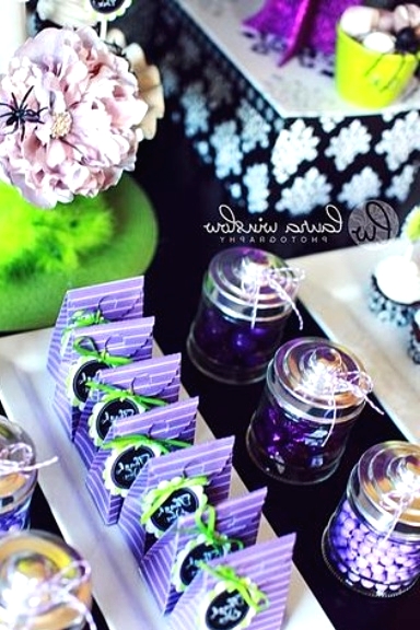 a bold purple, green and black Halloween sweets table with blooms and spiders plus sweets of various kinds is a very cool idea for a Halloween party