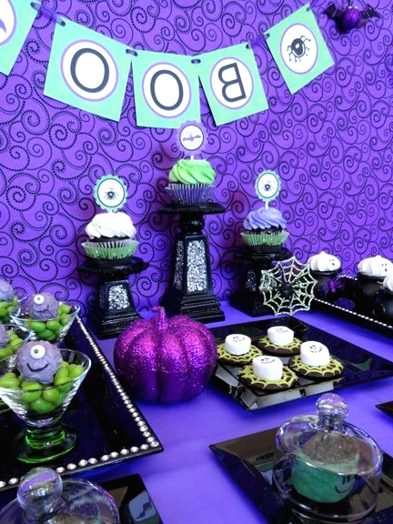 a bright purple, green and black Halloween sweets table with a glitter pumpkin, spiderwebs and various monsters is a very creative and fun idea for a kids' Halloween party