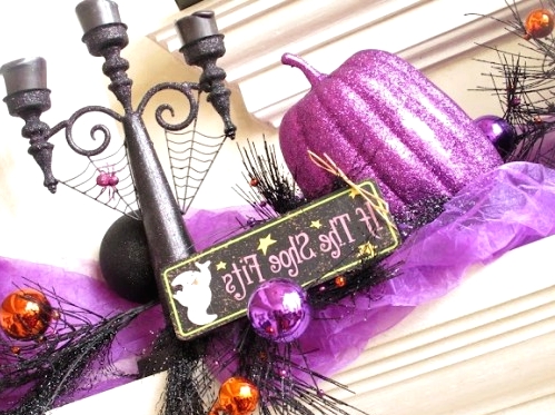 a Halloween mantel with a black candelabra, white candles, purple fabric and pumpkins, bold ornaments on branches is a cool idea