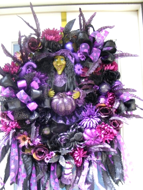 a very catchy and complicated looking Halloween wreath with feathers, ornaments, a witch, faux blooms, ribbons, bows and much, much more
