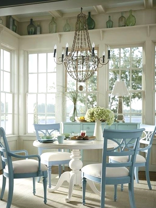 a shabby chic dining space with large French windows, a shelf with bottles, blue and white vintage furniture and a large chandelier
