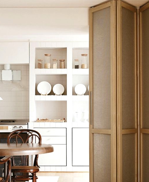 a pretty wood and fabric folding door is idea to separate a small kitchen and a dining space without making them even smaller and it matches the decor style