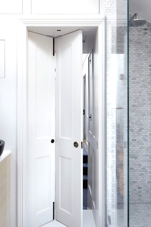 a white wood folding door is a great solution for a small bathroom - it doesn't make it smaller and it softens the decor of the space