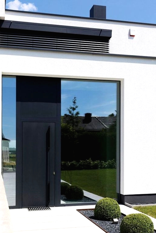 a large and a narrow window plus a black metal front door with an oversized handle on it is a cool solution for a modern house