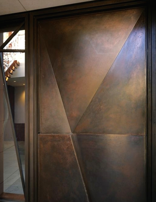 a modern geometric dark metal door with a 3D part and with a window by its side is a cool idea for a modern home