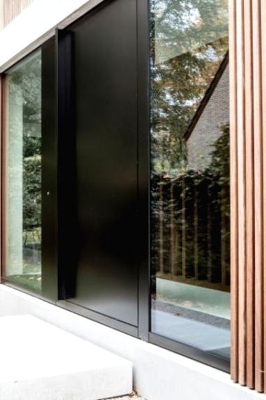 a sleek black metal front door and windows on both side of it is a cool idea for a modern or contemporary house, and will fit a minimalist one, too