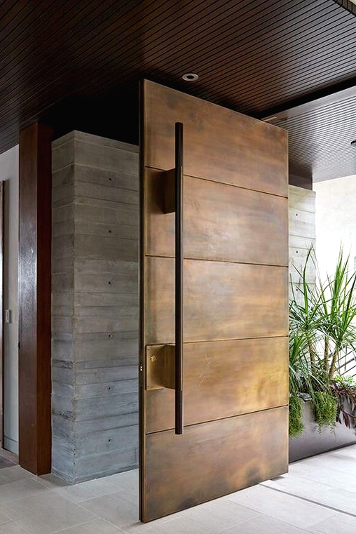 a weathered oversized metal front door with an oversized handle is a cool idea for a modern house and it makes a statement