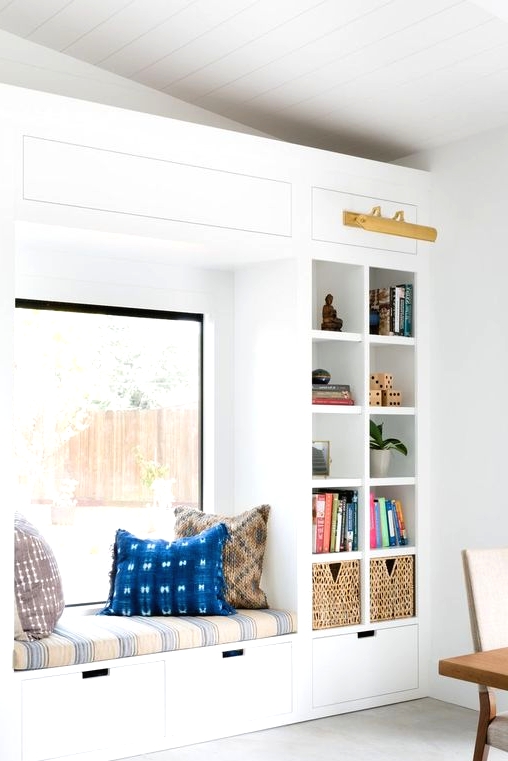 a bright contemporary reading nook with an upholstered bench, drawers and built-in shelves