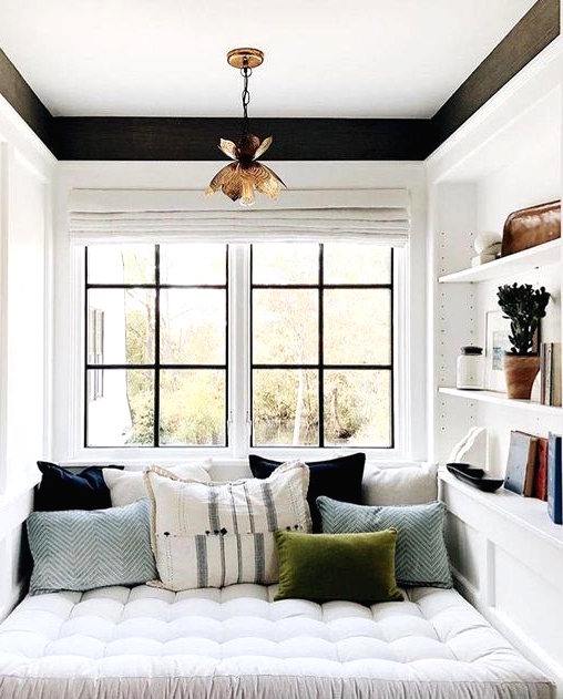 a small contemporary reading nook by the window, with some shelves built-in and colorful pillows