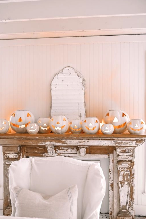 a shabby chic mantel styled with a lot of white jack-o-lanterns is a gorgeous and non-traditional idea for Halloween