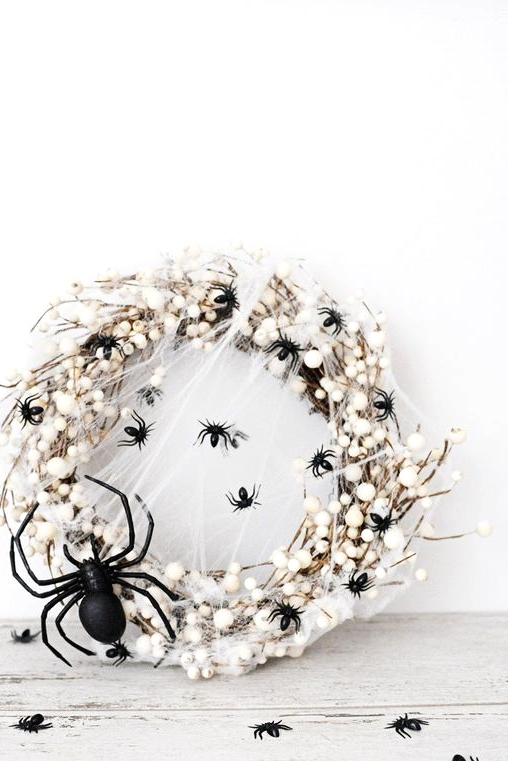 a white Halloween wreath imitating spider eggs covered with black spiders is a bold and catchy idea for your white Hallwoeen party