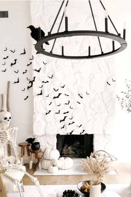 stacked white pumpkins, a skeleton on a chair, black bats and blackbirds are amazing to style your space for Halloween
