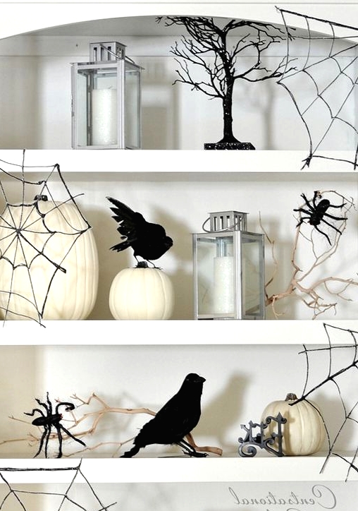 white niche shelves styled with white pumpkins, candles, owls, blackbirds, black spider web and black spiders are perfect