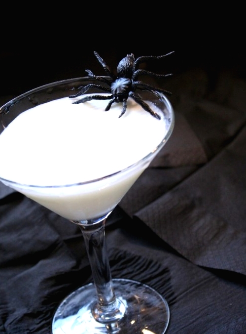 milk in a glass accented with a black spider is a bold and stylish idea for Halloween party that is easy to realize