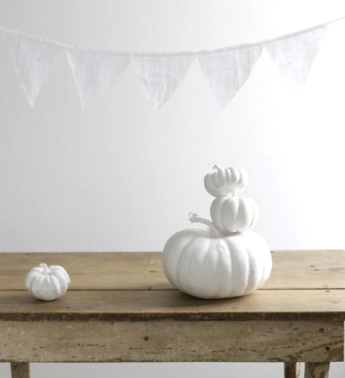pure white pumpkins and a white bunting are a great idea for decorating your home for Halloween in white and are easy to DIY