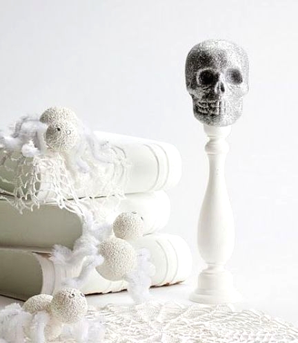 refined white Halloween decor with doilies, vintage books, yarn balls and a skull on a stand is a beautiful idea