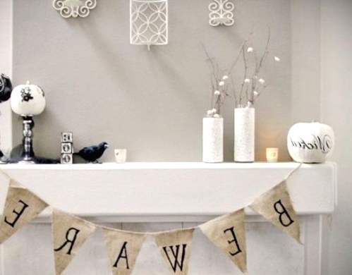 a white Halloween mantel with a burlap bunting, black and white pumpkins, white vases with branches with cotton buds is chic and out-of-the-box