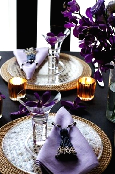 a super refined Thanksgiving tablescape with purple blooms and napkins, woven placemats, candles and beaded tassels