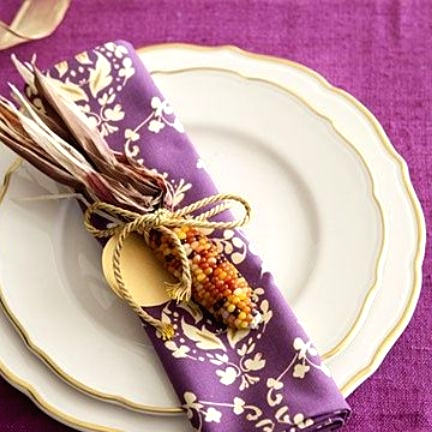 a bold purple Thanksgiving place setting with a purple tablecloth and a printed napkin, vintage plates and a corn cob for an accent