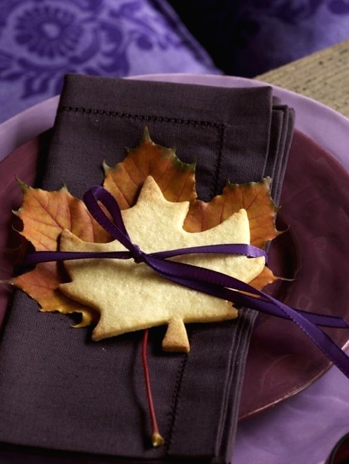 a bold purple place setting with bright purple fabric, purple layered plates, a brown napkin and a leaf cookie is amazing